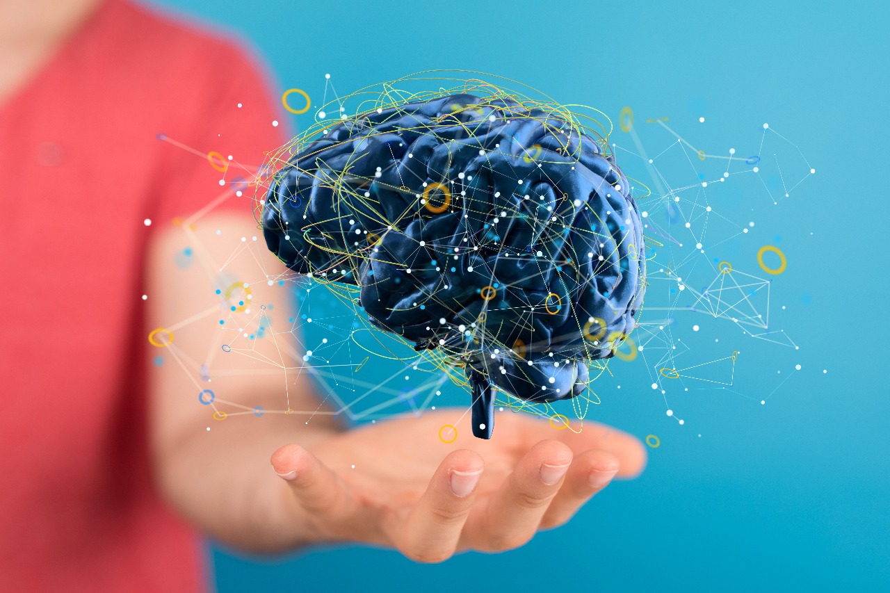 Human hand holding a digital brain with neural connections, symbolizing brain and behaviour science